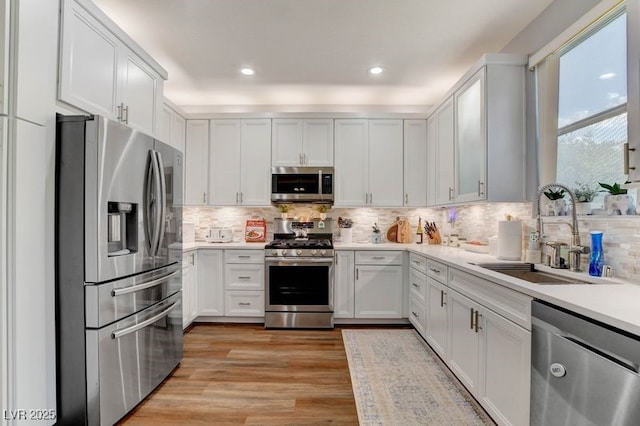 831 E Galingale Ct, Henderson, NV 89015 - kitchen featuring appliances with stainless steel finishes, a sink, light wood-style flooring, tasteful backsplash, and recessed lighting