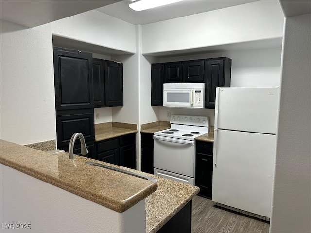 8000 Badura Ave Unit 1168, Las Vegas, NV 89113 - kitchen with white appliances, dark cabinets, light wood finished floors, and a peninsula