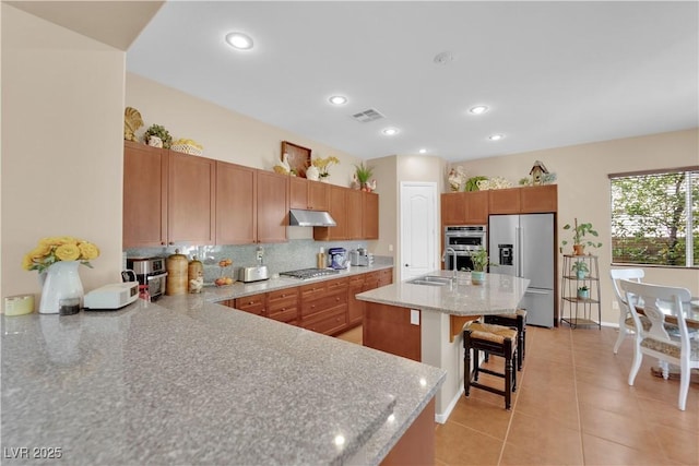 9375 Gold Lake Ave, Las Vegas, NV 89149 - kitchen with appliances with stainless steel finishes, a kitchen breakfast bar, under cabinet range hood, light tile patterned flooring, and light stone countertops