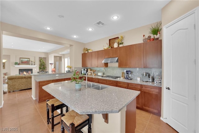 9375 Gold Lake Ave, Las Vegas, NV 89149 - kitchen with a sink, light tile patterned floors, light stone countertops, under cabinet range hood, and a breakfast bar