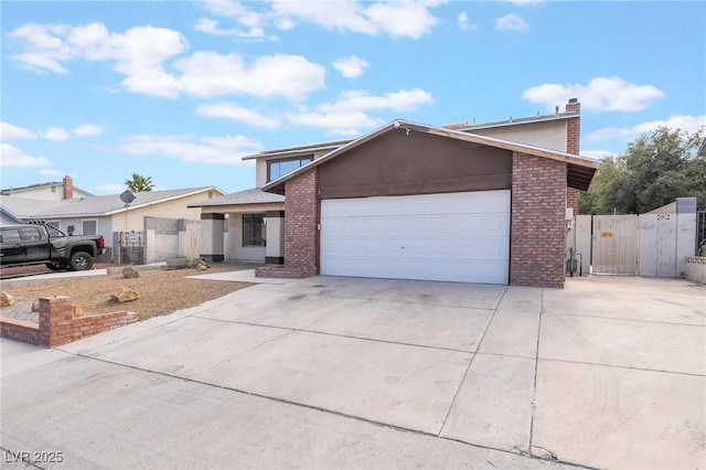 7009 Rawlins Ct, Las Vegas, NV 89128 - view of front of home with concrete driveway, brick siding, a garage, a chimney, and a gate