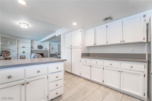 7009 Rawlins Ct, Las Vegas, NV 89128 - kitchen featuring white cabinets, a brick fireplace, light tile patterned floors, recessed lighting, and open floor plan