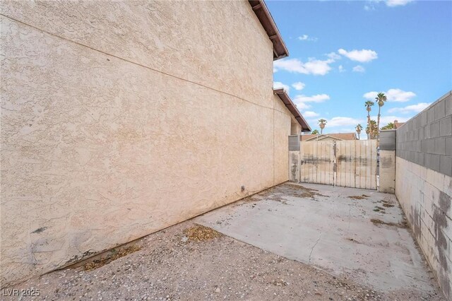 7009 Rawlins Ct, Las Vegas, NV 89128 - view of property exterior featuring stucco siding, a gate, and a patio area