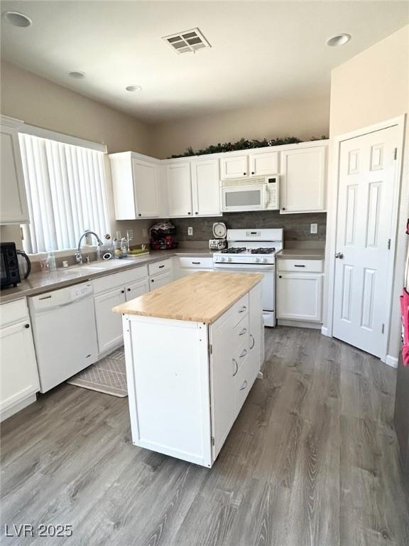 6812 Dipper Ave, North Las Vegas, NV 89084 - kitchen with white appliances, a sink, wood finished floors, white cabinetry, and recessed lighting