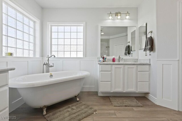 8121 Eagle Clan Ct, Las Vegas, NV 89131 - bathroom with a decorative wall, vanity, a freestanding bath, wainscoting, and wood finished floors