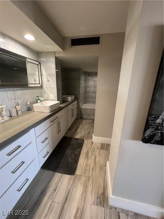 3111 Bel Air Dr Unit 22B, Las Vegas, NV 89109 - bathroom featuring a tub to relax in, vanity, wood finished floors, tasteful backsplash, and baseboards