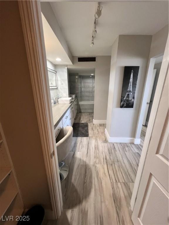 3111 Bel Air Dr Unit 22B, Las Vegas, NV 89109 - hallway featuring baseboards, a sink, track lighting, and light wood-style floors