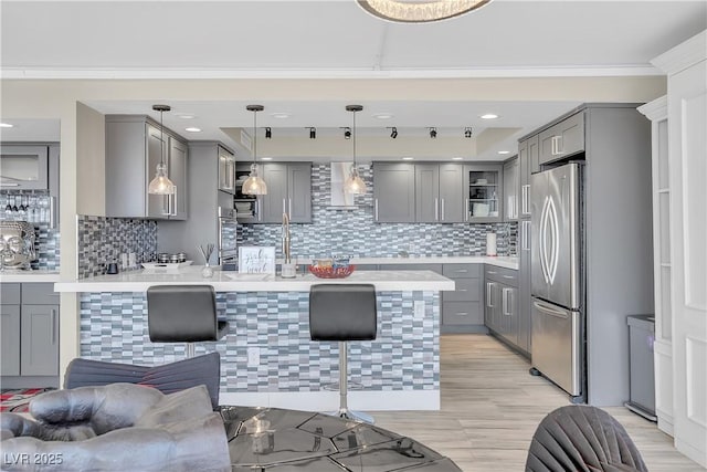 3111 Bel Air Dr Unit 22B, Las Vegas, NV 89109 - kitchen featuring gray cabinetry, appliances with stainless steel finishes, a kitchen breakfast bar, a peninsula, and wall chimney range hood