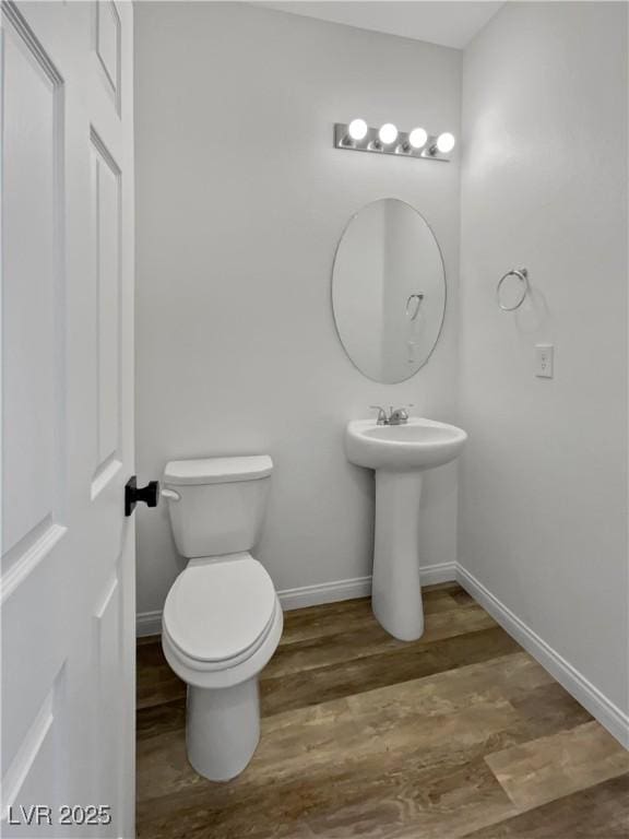 5709 Jaysin Douglas St, North Las Vegas, NV 89031 - half bath with baseboards, toilet, wood finished floors, and a sink