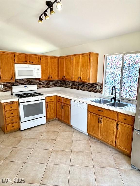 3665 Lucky Horseshoe Ct, Las Vegas, NV 89129 - kitchen featuring white appliances, a sink, backsplash, brown cabinetry, and vaulted ceiling