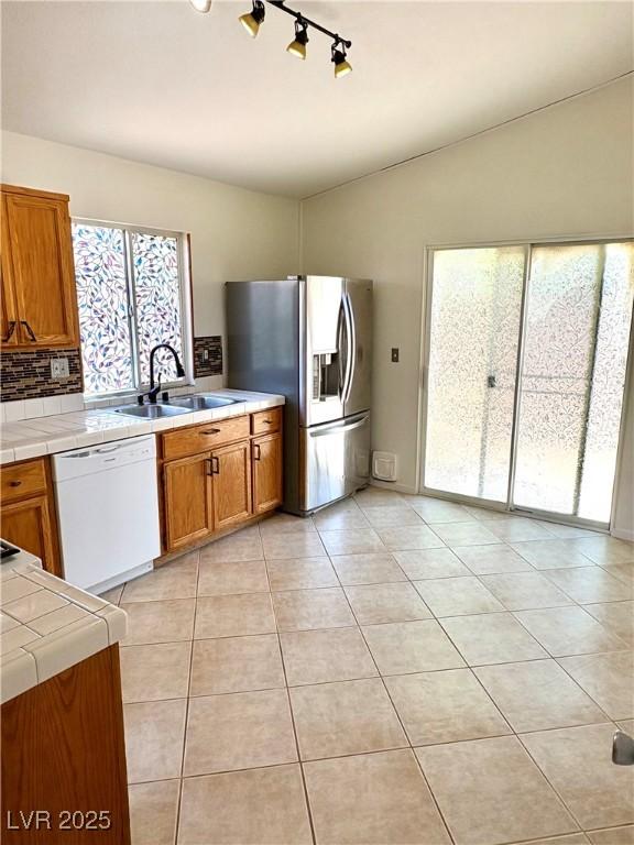 3665 Lucky Horseshoe Ct, Las Vegas, NV 89129 - kitchen with white dishwasher, a sink, stainless steel fridge with ice dispenser, tile counters, and plenty of natural light