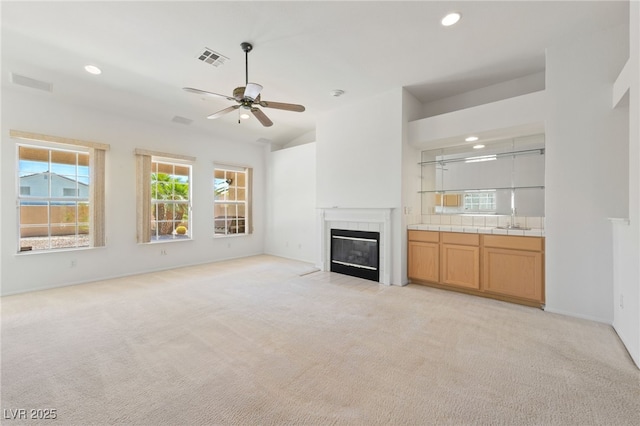 5232 Saranac Rd, Las Vegas, NV 89130 - unfurnished living room featuring light colored carpet, a tiled fireplace, ceiling fan, recessed lighting, and a sink