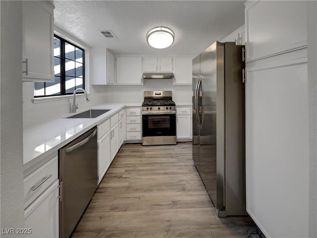 1832 Yellow Rose St, Las Vegas, NV 89108 - kitchen with appliances with stainless steel finishes, a sink, white cabinets, light wood finished floors, and a textured ceiling