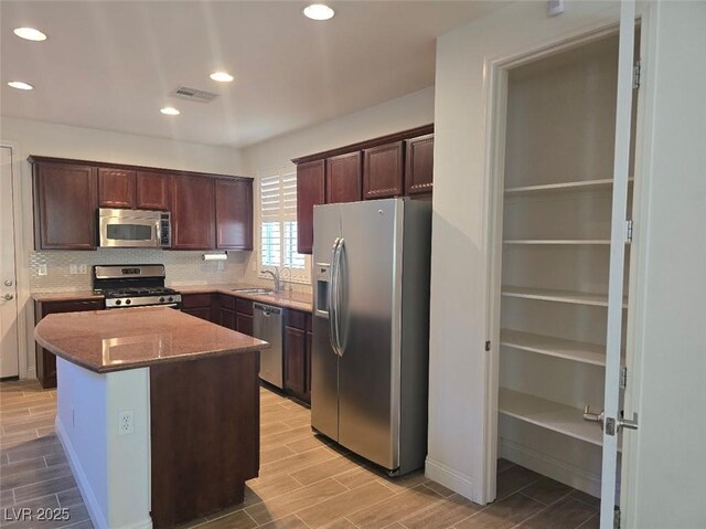 11298 Corsica Mist Ave, Las Vegas, NV 89135 - kitchen featuring appliances with stainless steel finishes, wood tiled floors, decorative backsplash, dark brown cabinets, and light stone counters