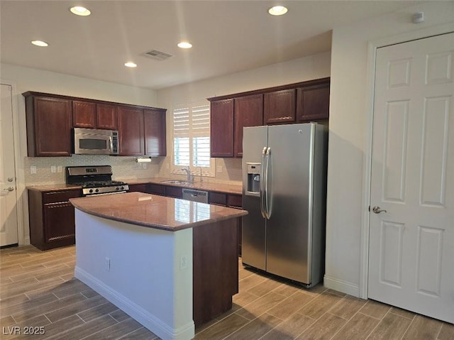 11298 Corsica Mist Ave, Las Vegas, NV 89135 - kitchen with appliances with stainless steel finishes, wood tiled floors, a center island, tasteful backsplash, and dark brown cabinetry