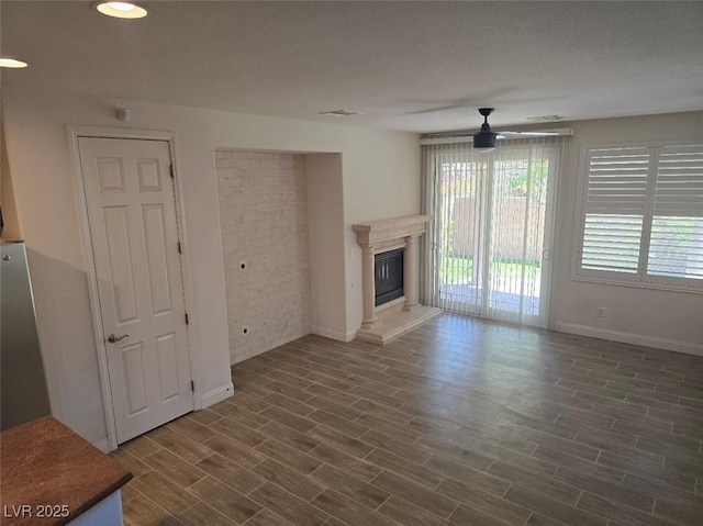 11298 Corsica Mist Ave, Las Vegas, NV 89135 - unfurnished living room featuring a ceiling fan, healthy amount of natural light, dark wood finished floors, and a fireplace