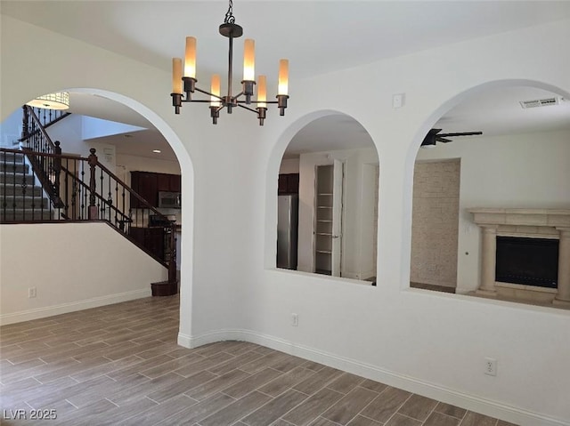 11298 Corsica Mist Ave, Las Vegas, NV 89135 - empty room with wood finished floors, stairs, a chandelier, a fireplace, and a ceiling fan
