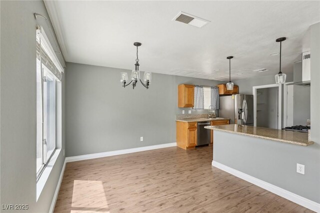4552 Aviation St, Las Vegas, NV 89115 - kitchen featuring appliances with stainless steel finishes, light wood-style floors, baseboards, and hanging light fixtures