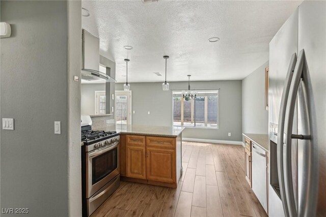 4552 Aviation St, Las Vegas, NV 89115 - kitchen featuring stainless steel appliances, light wood finished floors, hanging light fixtures, wall chimney exhaust hood, and a textured ceiling