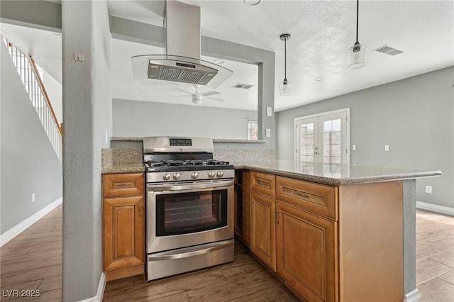 4552 Aviation St, Las Vegas, NV 89115 - kitchen with stainless steel range with gas cooktop, island exhaust hood, baseboards, ceiling fan, and light stone countertops