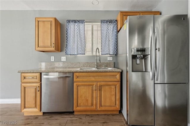 4552 Aviation St, Las Vegas, NV 89115 - kitchen with stainless steel appliances, a sink, light wood-type flooring, baseboards, and light stone counters