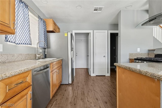 4552 Aviation St, Las Vegas, NV 89115 - kitchen featuring stainless steel appliances, wall chimney range hood, light wood finished floors, light stone countertops, and a sink