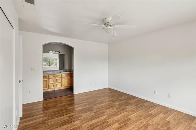 4552 Aviation St, Las Vegas, NV 89115 - empty room featuring wood finished floors, a ceiling fan, arched walkways, and a sink