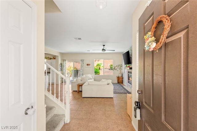 11226 Kenyan Sunshine Ct, Las Vegas, NV 89138 - entryway with a glass covered fireplace, stairway, light tile patterned floors, and a ceiling fan