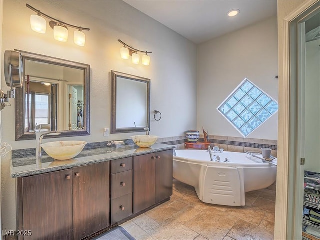 401 Obsidian St, Las Vegas, NV 89145 - full bathroom featuring double vanity, a garden tub, and stone tile floors