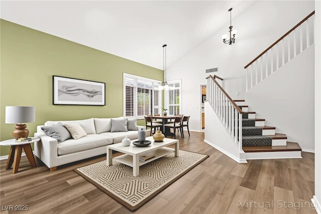 8612 Danza Del Sol Dr, Las Vegas, NV 89128 - living room featuring a chandelier, stairs, wood finished floors, and high vaulted ceiling