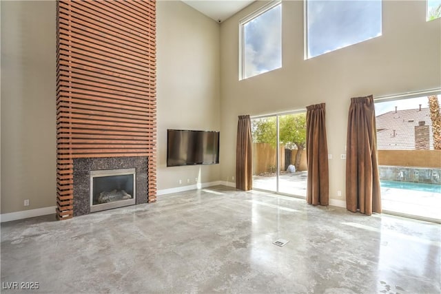 1448 Canyon Ledge Ct, Las Vegas, NV 89117 - unfurnished living room featuring concrete floors, a high ceiling, a fireplace, and baseboards