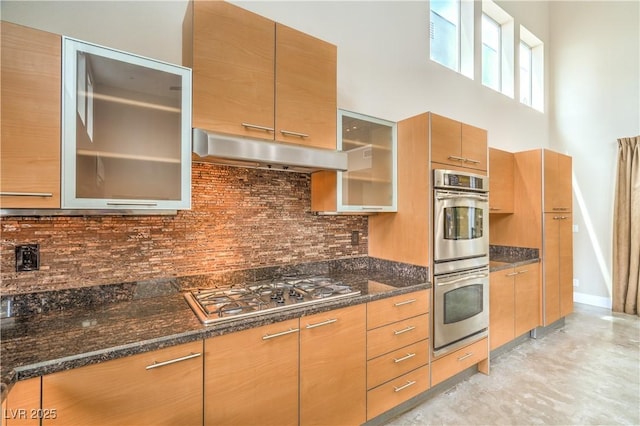 1448 Canyon Ledge Ct, Las Vegas, NV 89117 - kitchen featuring stainless steel appliances, under cabinet range hood, glass insert cabinets, dark stone countertops, and decorative backsplash