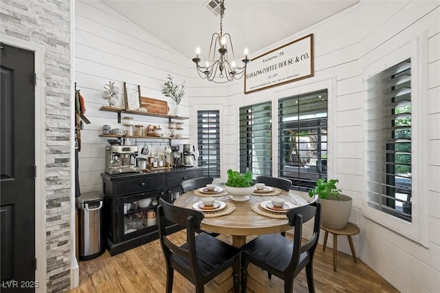 211 Kokopelli Ct, Henderson, NV 89074 - dining space featuring vaulted ceiling, a chandelier, wood finished floors, and wood walls