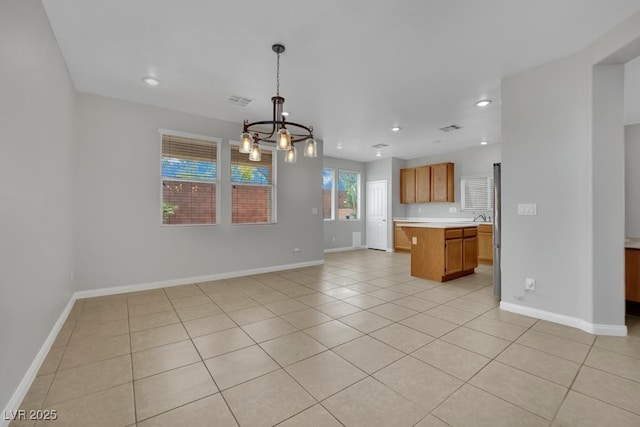 11787 Fern Creek Ln, Las Vegas, NV 89183 - kitchen featuring a chandelier, light countertops, light tile patterned flooring, brown cabinets, and baseboards