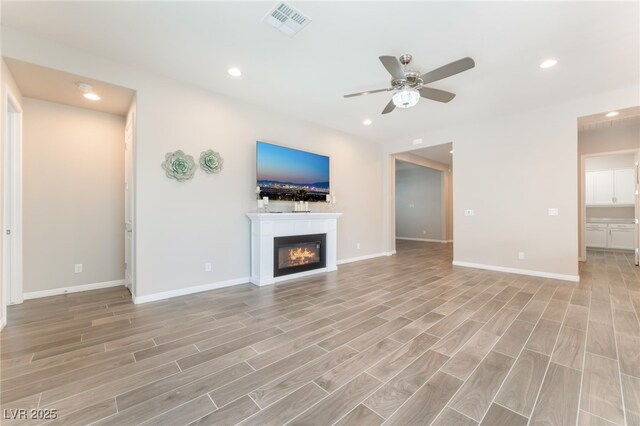 421 Point Sur Ave, Las Vegas, NV 89138 - unfurnished living room with a ceiling fan, recessed lighting, a glass covered fireplace, light wood-style floors, and baseboards