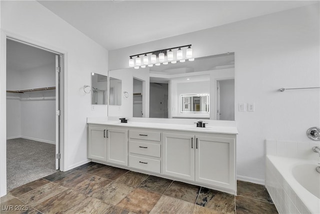 576 Foster Springs Rd, Las Vegas, NV 89148 - bathroom featuring double vanity, a garden tub, a walk in closet, and baseboards