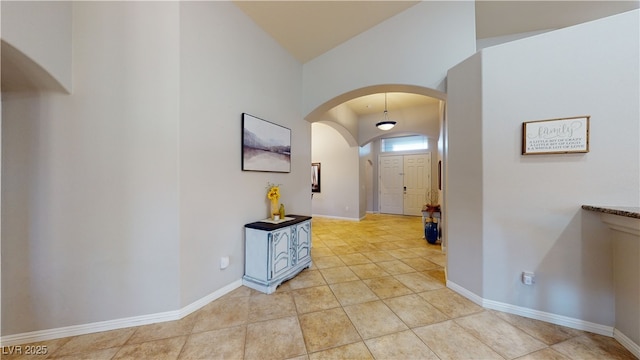 2713 Tanagrine Dr, North Las Vegas, NV 89084 - hallway featuring arched walkways, lofted ceiling, baseboards, and light tile patterned floors