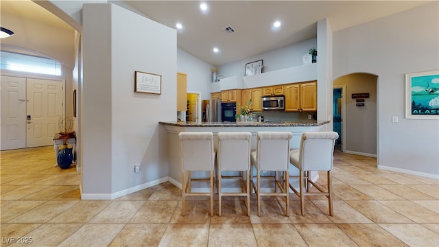 2713 Tanagrine Dr, North Las Vegas, NV 89084 - kitchen with stainless steel appliances, high vaulted ceiling, arched walkways, baseboards, and a breakfast bar