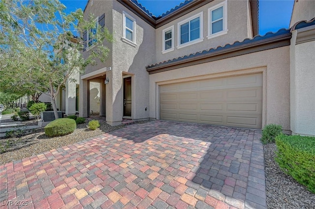 5244 Fiery Sky Ridge St, Las Vegas, NV 89148 - view of front of home with a tiled roof, an attached garage, stucco siding, and decorative driveway
