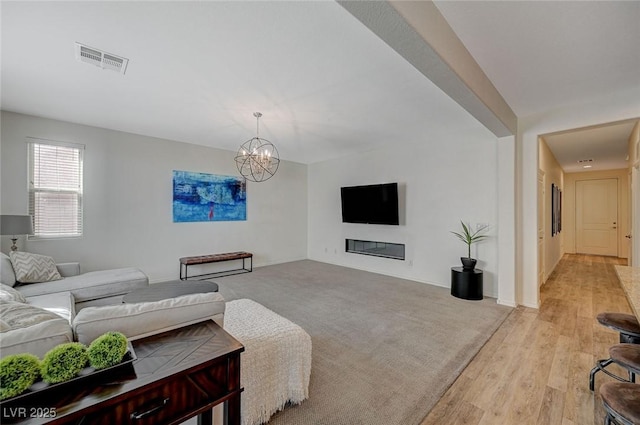 5244 Fiery Sky Ridge St, Las Vegas, NV 89148 - living area with a chandelier, light wood-type flooring, baseboards, and a glass covered fireplace