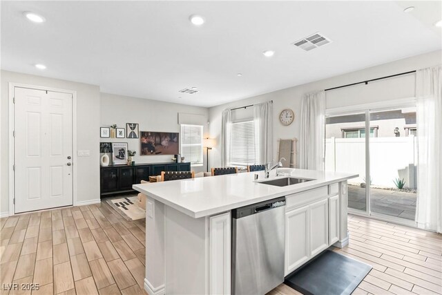 7350 N Decatur Blvd Unit 5, Las Vegas, NV 89131 - kitchen with stainless steel dishwasher, a sink, wood tiled floors, white cabinets, and a kitchen island with sink