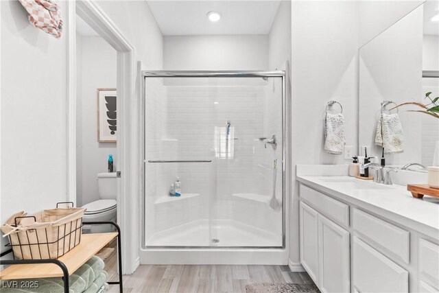 7350 N Decatur Blvd Unit 5, Las Vegas, NV 89131 - bathroom featuring a stall shower, toilet, vanity, wood finished floors, and recessed lighting