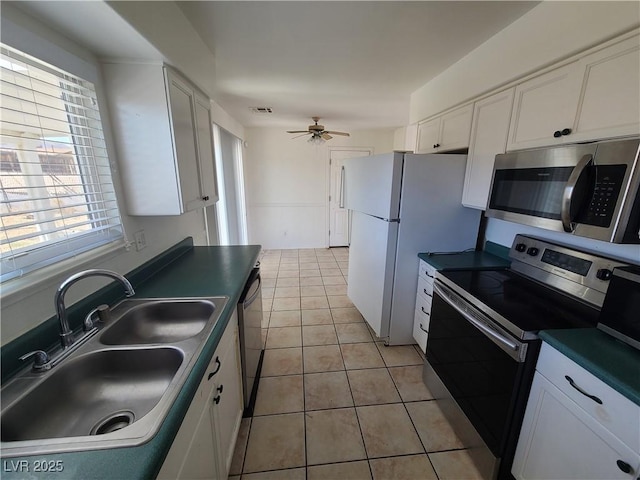 129 Maple St, Henderson, NV 89015 - kitchen featuring appliances with stainless steel finishes, a sink, dark countertops, white cabinets, and plenty of natural light