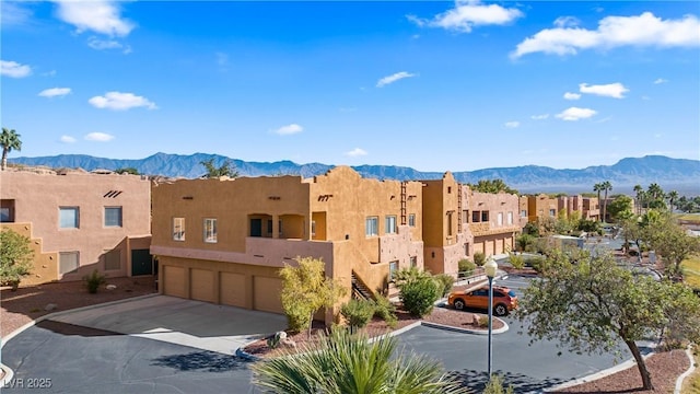 728 Hardy Way Unit E, Mesquite, NV 89027 - view of building exterior featuring an attached garage, a mountain view, driveway, and a residential view