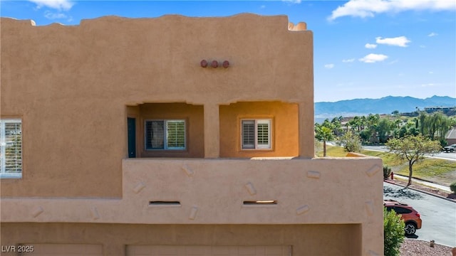 728 Hardy Way Unit E, Mesquite, NV 89027 - view of property exterior with a mountain view, a garage, and stucco siding