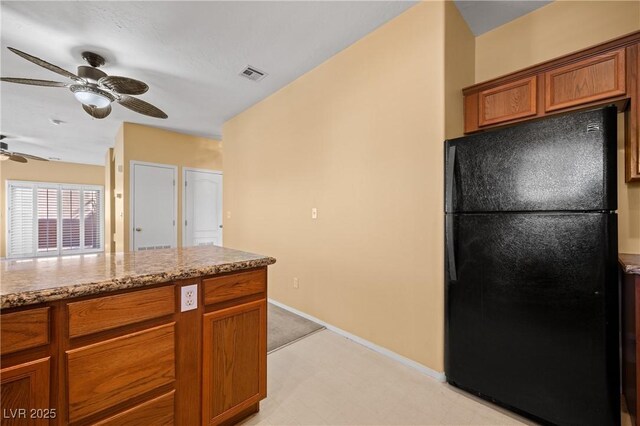 728 Hardy Way Unit E, Mesquite, NV 89027 - kitchen featuring freestanding refrigerator, ceiling fan, brown cabinets, baseboards, and light stone countertops