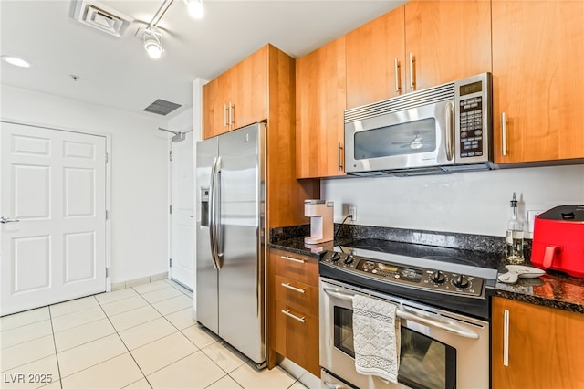 200 W Sahara Ave Unit 3303, Las Vegas, NV 89102 - kitchen with appliances with stainless steel finishes, brown cabinetry, light tile patterned flooring, and dark stone countertops