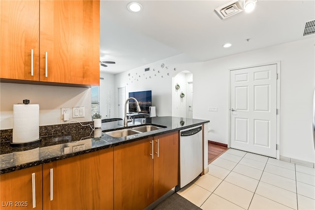 200 W Sahara Ave Unit 3303, Las Vegas, NV 89102 - kitchen with stainless steel dishwasher, a sink, brown cabinetry, arched walkways, and dark stone counters