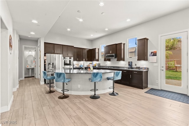 245 Hull St, Henderson, NV 89015 - kitchen featuring stainless steel appliances, a kitchen breakfast bar, dark brown cabinetry, light wood finished floors, and recessed lighting