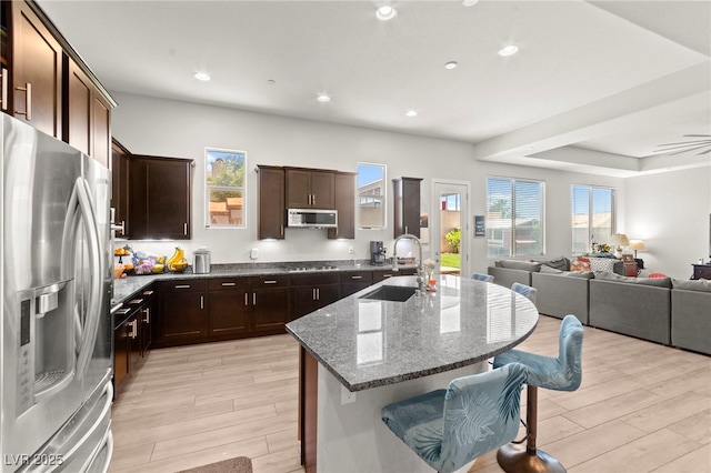 245 Hull St, Henderson, NV 89015 - kitchen featuring appliances with stainless steel finishes, a sink, open floor plan, a breakfast bar area, and dark stone counters